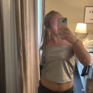 Silver axelbandslös tubtopp Kappahl XS - Snygg axelbandslös tubtopp i  silver från Kappahl. Prislapp kvar då jag inte fått någon användning för toppen💗