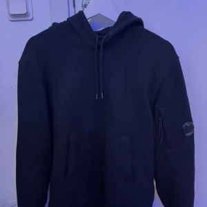 Svart hoodie från C.P. Company - Svart hoodie från C.P. Company i nyskick. Köpt på urban modern. Storlek M och passar mig bra som är cirka 180cm. 