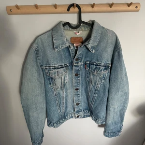 Levi's vintage blå jeansjacka - Säljer en vintage blå jeansjacka från Levi's. Jackan har två bröstfickor med knappar, snygga söm-detaljer och den typiska röda Levi's-taggen. Perfekt för lager-på-lager och funkar året runt. Materialet är slitstarkt denim i 100% bomull. Står ingen storlek men skulle säga att den är i storlek M eller S men passar xs också. Har en lite oversized passform. Köpt på vintage butik men aldrig använd själv och är i mycket bra skick utan några defekter.