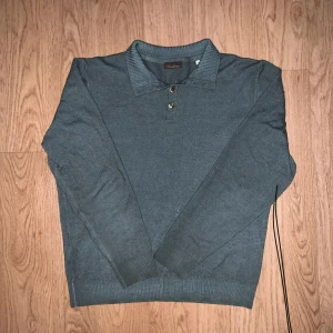 Mörkgrön merinoull pikétröja från Stenströms  - Snygg grå pikétröja från Stenströms i 100% merinoull. Klassisk krage med två knappar och långärmad modell. Perfekt för dig som gillar stilrena och bekväma plagg med premiumkänsla. Passar dig som vill ha en tidlös look. Storlek M men passar S