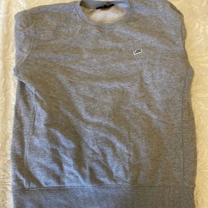 Grå sweatshirt från Lee i bomull - Säljer en stilren grå sweatshirt från Lee i regular fit. Tröjan har rund halsringning, diskret Lee-logga på bröstet och ribbade muddar vid ärmslut och nederkant. Perfekt för en chill och enkel look.