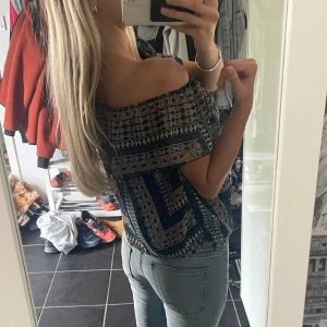 Blå mönstrad offshoulder topp - Säljer en snygg offshoulder topp med blått och svart geometriskt mönster. Toppen har volang upptill och är croppad, perfekt till jeans eller kjol. Lätt och luftig, passar dig som gillar boho-vibe och vill sticka ut lite extra.