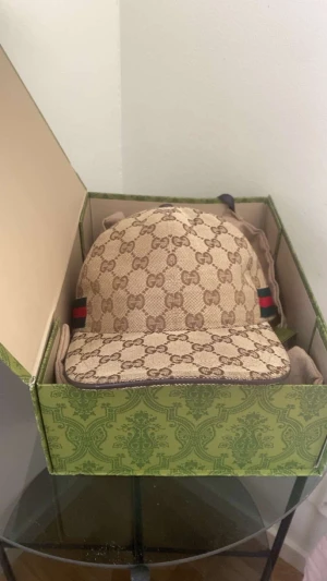Gucci GG Supreme keps beige - Säljer en beige Gucci keps i klassiskt GG Supreme-mönster. Kepsen har bruna detaljer, böjd skärm och ikoniska gröna och röda ränder på sidorna. Tillverkad i canvas med justerbart band bak. Kommer i originalkartong och dustbag. Möts upp i Stockholm 