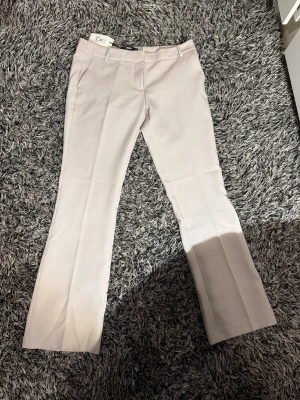 Begie Kostymbyxor🍪🤍 - Helt oanvända beige kostymbyxor från Bikbok. Prislappen är fortfarande kvar och byxorna är fortsatt i ett mycket gott skick. Kostymbyxorna är utsvängda/bootcut och i storlek 40. 🙌🙌🤍🤍