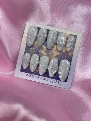 Butterfly (XS); Medium Almond - Snygga handgjorda press-on naglar i glittrigcateye vit färg med 3D nailart linjer, fjärilsdekor och pärlor. Naglarna har en medium almond form och kommer i XS: 14 mm, 11 mm, 11,5 mm, 10 mm, 8 mm. Perfekt för dig som vill ha en unik och trendig look.