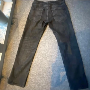 Svarta jeans från Jack & Jones - Säljer ett par svarta jeans från Jack & Jones med klassisk femficksdesign. Jeansen har rak passform och är tillverkade i ett mjukt denimtyg som sitter snyggt. Perfekta för dig som gillar stilrena och enkla jeans. Storlek 32/30 jag köpte dom för 599kr och säljer nu för 399kr