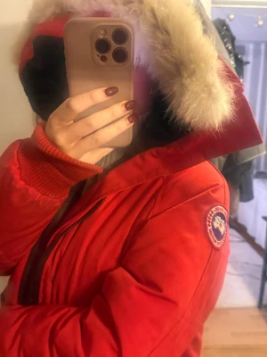 Röd Canada Goose jacka med päls - Säljer en röd Canada Goose dunjacka med en äkta päls på huvan. Perfekt nu för de kalla vinterdagarna!😍 Pris går att diskuteras!!! 