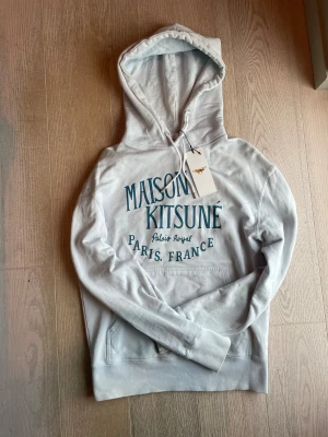 Maison Kitsuné vit hoodie med tryck - As deg Ljus blå hoddie ifrån masion kistune jag köpte den i Paris för 4 tusen och säljer den nu för endast 699 pris går att diskutera vid snabba affär🌟🌟 Den är använd med väldigt fin försiktighet och har kvar nästan allt og