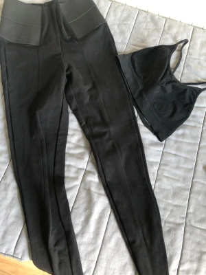 Svarta tighta leggings med hög midja - Säljer ett par svarta leggings med hög midja och bred linning. De är tighta och har en stilren look som passar perfekt till träning eller chill. Materialet är mjukt och stretchigt för maximal komfort.