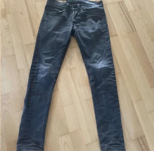 Svarta dondup skinnet jeans - Säljer ett par svarta skinny jeans från dondup med klassisk femficksdesign och smal passform. Jeansen har en mörk tvätt och är tillverkade i stretchigt bomullsmaterial för en tajt look. Perfekta för dig som gillar en slimmad siluett.