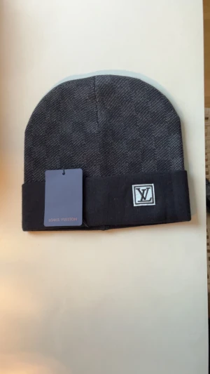 Mörkgrå mössa från l v  - Snygg mörkgrå mössa från l v som passar perfekt nu när vintern kommer. När man vill ha något varmt på huvudet eller så passar det lika bra som present