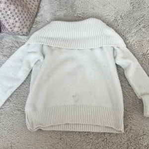 Vit stickad tröja med bred krage Lindex - Supermysig vit stickad tröja från Lindex med bred ribbad krage som kan bäras offshoulder. Tröjan har långa ärmar och ribbade muddar vid ärmslut och nederkant. Perfekt för kyliga dagar när du vill vara både varm och stilren.