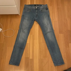 Replay Anbass ljusblå jeans - Säljer ett par Replay Anbass jeans i ljusblå tvätt med klassisk femficksdesign och snygga detaljer på bakfickorna. Jeansen har en slim passform och raka ben, tillverkade i mjukt denimtyg som sitter skönt hela dagen.