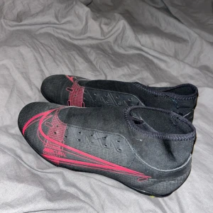 Nike Mercurial svarta fotbollsskor - Säljer ett par svarta Nike Mercurial fotbollsskor med röda detaljer och gula dobbar. Bra skick utan skosnören använda ett par gånger men inga skador på själva skon.