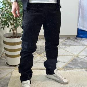 Svarta Replay jeans Anbass herr - Säljer ett par svarta Replay Anbass jeans med klassisk femficksdesign och diskret logga på bakfickan. Jeansen har rak passform och är tillverkade i mjukt bomullsmaterial med lite stretch för extra komfort. Perfekta för dig som gillar stilrena och snygga jeans.