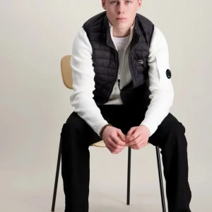 Tonår Svart dunväst från Colmar - Svart dunväst från Colmar stl 160 tonår med quiltad design och två dragkedjeförsedda fickor. Västen har en hög krage och Colmar-logga på bröstet. Perfekt att slänga över en hoodie eller tröja för extra värme. Snygg och stilren look som funkar året runt.