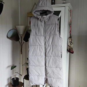 Lång fodrad väst strl S - Lång fodrad väst strl S från H&M.                     Ljusbeige.                                                                                       Luva & 2 fickor.                                                     