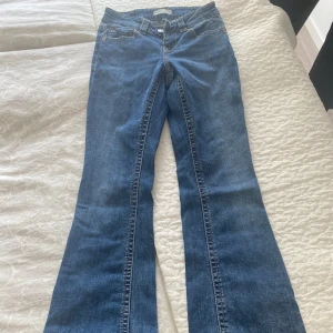 Blå bootcut jeans från Perfect Jeans - Snygga blå bootcut jeans från Gina tricot med klassiska fickor bak och fram, samt dekorativa knappar på bakfickorna. Jeansen är i petite och passar perfekt dig som är 160 eller kortare. Jeansen är tillverkade i mjukt denimtyg med tydliga sömmar och bälteshällor. 