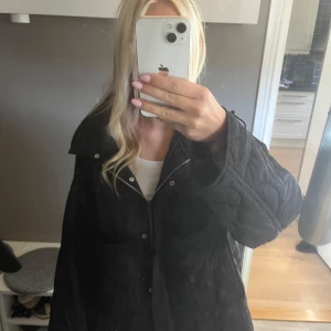 Svart quiltad jacka med dragkedja Zara  - Säljer en svart quiltad jacka med oversized passform och stora ärmar. Jackan har dragkedja och tryckknappar framtill samt en hög krage. Perfekt för höst och vinter när du vill vara både varm och snygg.