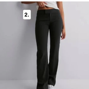 Svarta bootcut kostymbyxor - Snygga svarta kostymbyxor med bootcut-modell och hög midja. Byxorna har en klassisk look med diskret knäppning framtill och raka ben som släpper ut vid ankeln. Perfekta för en stilren och trendig outfit.