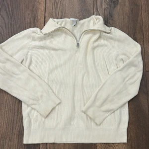 Beige half zip-tröja H&M - Säljer en beige ribbad tröja från H&M med half zip och hög krage. Slim fit-modell med långa ärmar och mjukt material som känns skönt mot huden. Perfekt för lager-på-lager och enkel att styla till olika outfits.