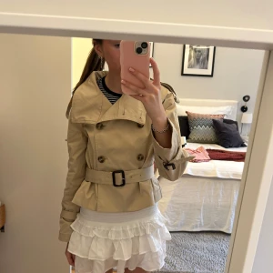 Hm trenchcoat  - Populär kort trenchcoat från hm med knappar och bälte i strl 32💓slutsåld och svår att få tag på! Väldigt eftertraktad! I nyskick😇💕så så fin!😍perfekt nu till hösten! Passar en xs/s!🩷