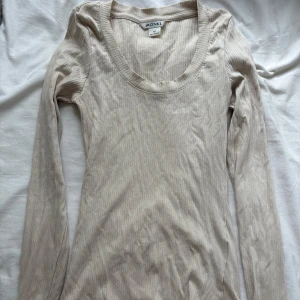 Beige ribbad långärmad tröja Monki - Säljer en beige ribbad långärmad tröja från Monki i storlek XS. Tröjan har en rundad halsringning och är tillverkad i ett mjukt, stretchigt material som sitter snyggt på kroppen. Perfekt att styla med jeans eller kjol.