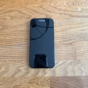 iPhone 15 - Snygg svart iPhone 15 i gott skick. Skärmen och baksidan är fria från synliga repor eller sprickor. Dubbelkamera och modern design. Alla knappar och portar ser hela ut. Perfekt för dig som vill ha en pålitlig och kraftfull mobil med senaste funktionerna.
