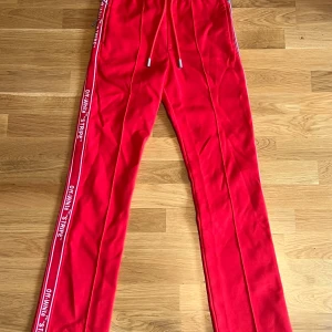  Off-White Trackpants röd - Riktigt snygga röda byxor från Off-White med vita stripes och text längs sidorna. Byxorna har dragsko i midjan och en dragkedja på baksidan. Tyvärr för små för mig men väldigt häftiga