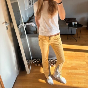 Gula low-waisted byxor med dragkedjor - Snygga gula bootcut-byxor med grå insida vid bensluten och råa kanter. Byxorna har låg midja, dekorativa dragkedjor på bakfickorna och dubbla knappar fram. Perfekta för dig som vill sticka ut med färg och coola detaljer.🔥🔥❤️❤️