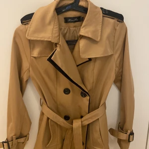 Beige trenchcoat med bälte stl S - Snygg beige trenchcoat i storlek S. Mycket bra skick, knappt använd.