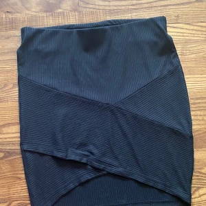 Svart ribbad kjol från Gina Tricot - Svart kortkjol från Gina Tricot i ribbat tyg. Kjolen har en tight passform.