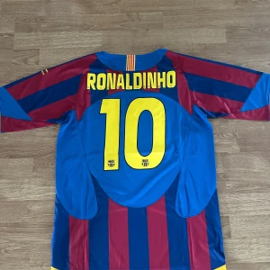 FC Barcelona retro tröja - En klassisk retro FC Barcelona fotbollströja med trycket Ronaldinho 10 på ryggen. En väldigt unik tröja för alla Barca samt Ronaldinho älskare. Helt ny!!