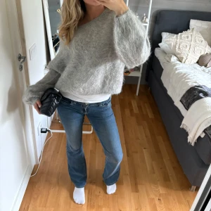 Blå bootcut jeans med kontrastsömmar - Snygga blå jeans med bootcut-modell och vita kontrastsömmar på bakfickorna. Klassisk femficksdesign och låg midja. Jeansen har en lätt utsvängd passform nertill och är perfekta för en avslappnad stil.