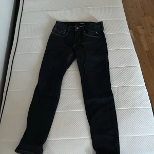 Replay Anbass mörkblå jeans, stl 28/32 - Säljer ett par mörkblå Replay Anbass jeans i storlek 28/32. smal passform och snygga kontrastsömmar. Tillverkade i stretchig denim för extra komfort. Perfekta för dig som gillar en modern och stilren look.
