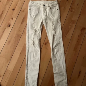 Vita jeans från Dr Denim x Fiorucci - Vita jeans från Dr Denim Jeansmakers från Fiorucci med slitna detaljer framtill. Klassisk femficksmodell, låg midja och stretchigt material i bomull och elastan. 