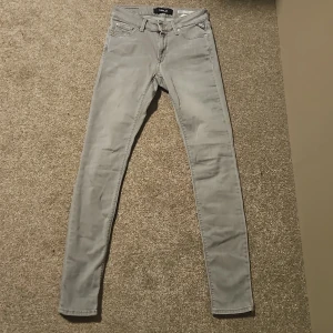 Grå skinny jeans från Replay W28 L32 - Snygga grå skinny jeans från Replay, modell Luzien. Jeansen har klassisk femficksdesign, dragkedjegylf och smal passform hela vägen ner. Tillverkade i mjukt denimtyg med stretch för extra komfort. Perfekta för dig som gillar en stilren och modern look.