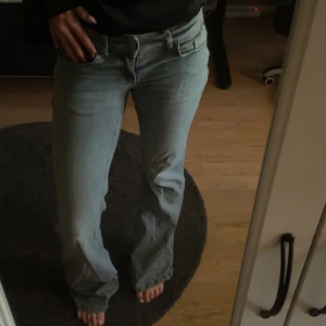 Ljusblå bootcut jeans - Säljer ett par ljusblå jeans med bootcut-modell och låg midja. Jeansen har klassiska fem fickor och stängs med dragkedja och knapp. Perfekta för dig som gillar en avslappnad och trendig look. Materialet är jeans i bomull. Lite slitna längst ner så dem är väldigt långa💕