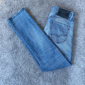 Replay jeans - Säljer ett par snygga ljusblå jeans från Replay med klassisk femficksdesign och diskreta slitningar. Jeansen har raka ben och normal passform, midwaist och är tillverkade i mjukt jeanstyg. Perfekta för dig som gillar en avslappnad stil.