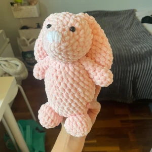 Virkad kanin  - Bilderna visar en söt, handvirkad rosa kanin i mjukt garn. Detta är en gosedjur/leksak som man även kan ha som prydnad. Gemför storlek med min hand 