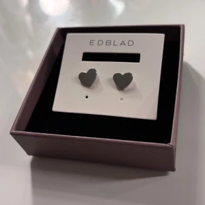 Hjärtörhängen från Edblad - Stilrena hjärtörhängen från Edblad i blankt rostfritt stål. Dem är i mycket bra skick och levereras i sin originalask.