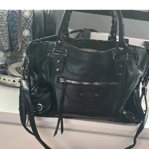 Balenciaga liknande väska  - Påminner om balenciaga city bagen, aldrig använd. Köpt på en marknad i Spanien, men har somsagt tyvärr inte blivit använd. Passar till skolan/jobba då de får plats en del, ex dator, böcker osv. Måtten är:  12 cm djup (botten på väskan), 37 cm bred, 22 cm hög Skriv om du undrar något!🩷