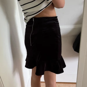 Svart sammetskjol med volang -  svart sammetskjol med volangkant nertill. Använd 1 gång 