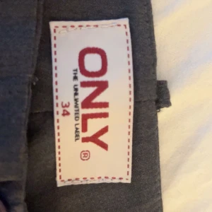 Grå kostymbyxor från ONLY, stl 34 - Snygga gråa kostymbyxor från ONLY i storlek 34. Byxorna har raka ben utsvängda ner till bälteshällor och diskreta fickor bak. Perfekt för en clean och stilren look. Materialet känns mjukt och följsamt, vilket gör dem bekväma hela dagen. Lågmidjade !!!