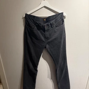 Lee jeans - Säljer ett par svarta Lee Rider jeans med klassisk femficksdesign och raka ben. Jeansen har normal passform och är tillverkade i mjukt bomullsmaterial med lite stretch. Perfekta för dig som gillar en stilren och enkel look. Passar runt 180 cm