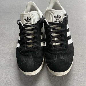 Adidas Gazelle svarta sneakers mocka - Klassiska Adidas Gazelle sneakers i svart mocka med vita detaljer och de ikoniska tre ränderna på sidan. Skorna är använda men i bra skick! Skriv privat för fler bilder!