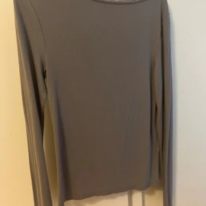 Beige långärmad topp från 157 - En stilren beige långärmad topp från 157 i storlek S. Toppen har en enkel, rak passform och är tillverkad i ett mjukt och stretchigt material. Säljer då den inte kommer till användning!