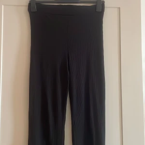 Svarta ribbade  vida byxor  - Snygga svarta byxor med ribbad struktur och utsvängda ben. Hög midja och stretchigt material!