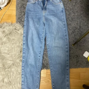 Ljusblå jeans  - Säljer ett par ljusblå jeans från gina perfect jeans i storlek 34. De har klassisk femficksdesign, raka ben och hög midja. Jeansen är tillverkade i bomull och har en snygg, enkel look som passar till det mesta. Perfekta för dig som gillar en clean och tidlös stil.