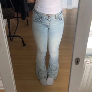 Ljusblå bootcut jeans med hög midja - Snygga ljusblå jeans med bootcut och hög midja. Jeansen har klassisk femficksdesign, dragkedja och knapp framtill. Tillverkade i jeansmaterial med lätt tvättad look och subtila slitningar. Har lite missfärgningar men man ser knappt om man inte kollar skit noga, gått sönder bara lite av ena sidan men ser knappt heller det